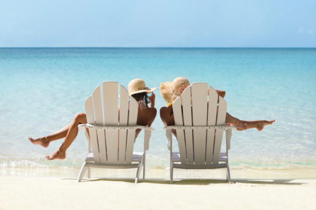 two women relaxing in adirondack chairs on a tropical beach